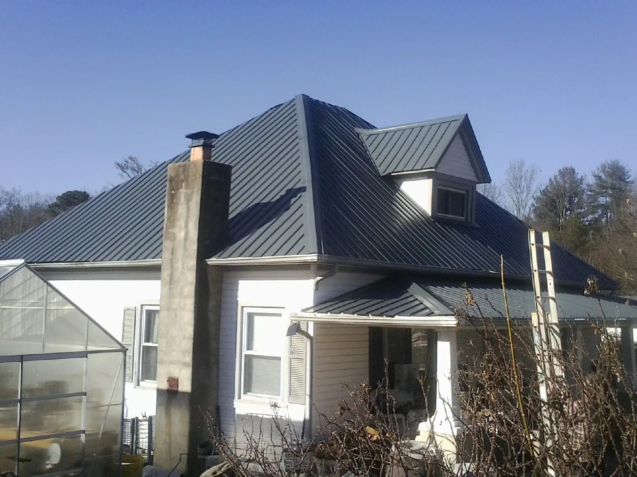 Dark blue standing seam metal roof on a white farmhouse with dormer — Slate & Tile Roof Repair by Roofing Brothers in Colville
