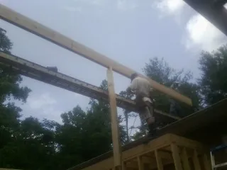 Carpenter setting a ridge beam over a new addition frame — Ice Dam Removal by Roofing Brothers in Colville