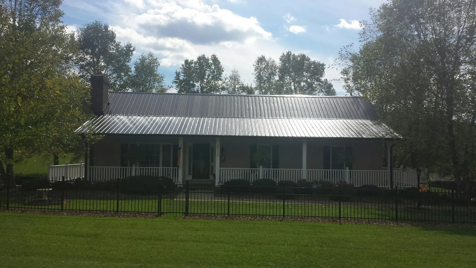 Gray metal roof on a brick ranch with a full width front porch — Gutter Guard Installation work by our crew in Colville