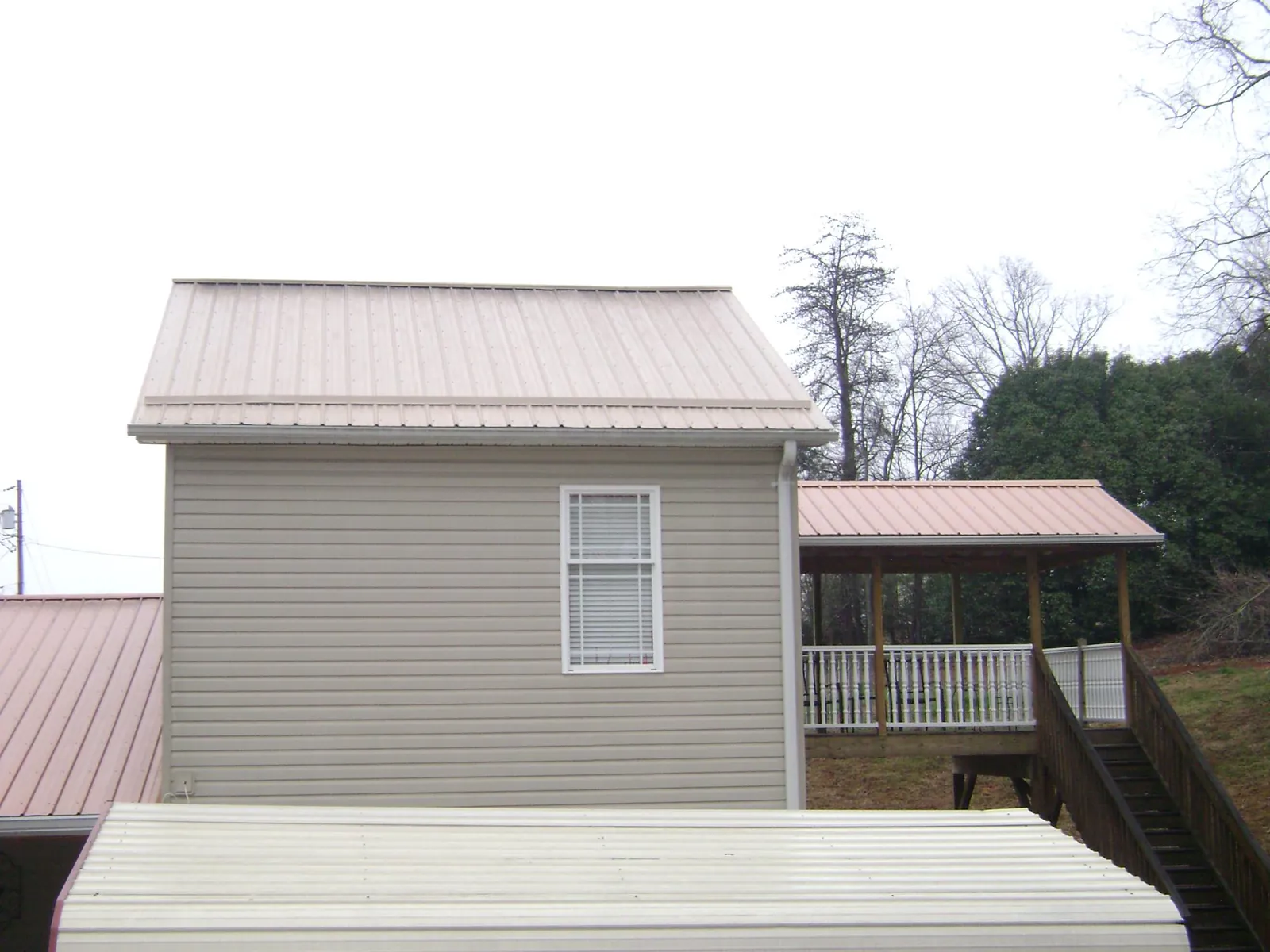 Tan metal roofs on a two story addition and attached porch, from a Roof Replacement job in Colville