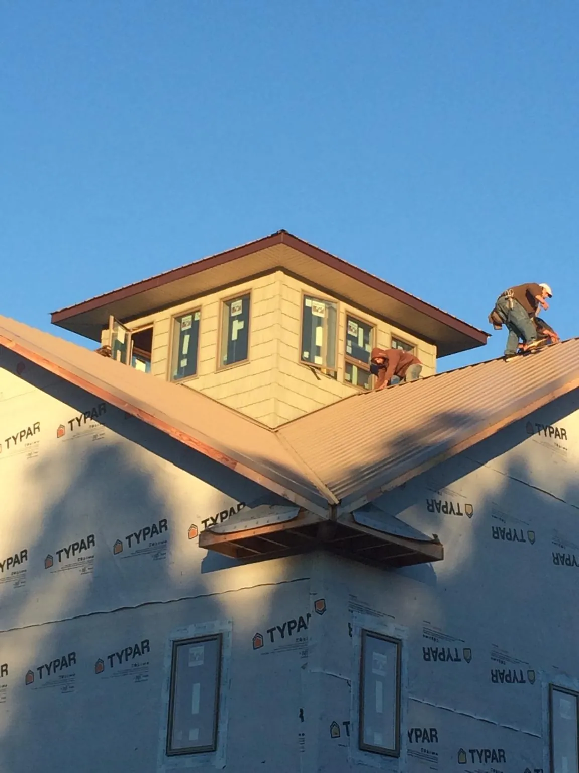 Roofers working around a rooftop cupola on a new metal roof at sunset — Roof Waterproofing in Colville by Roofing Brothers